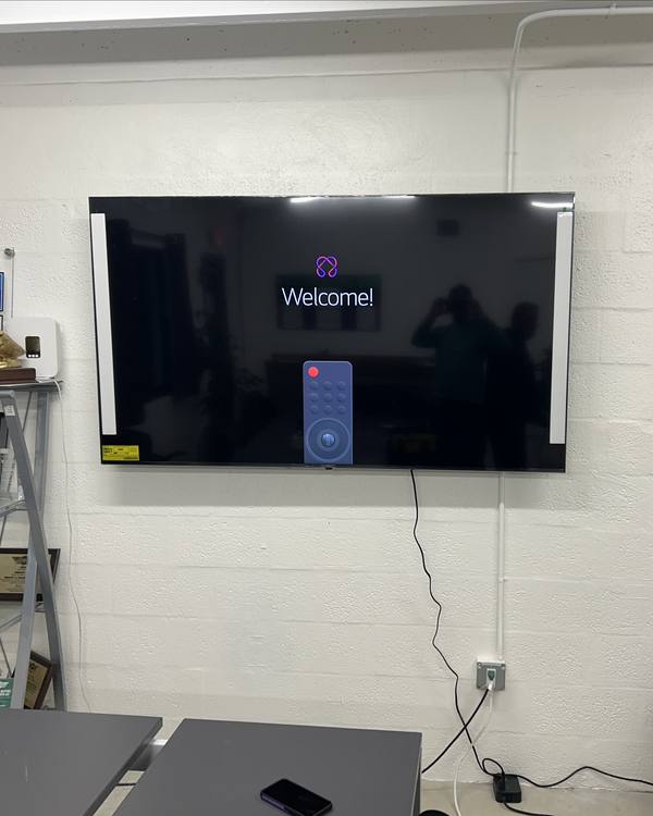 TV mounted on an office wall with cables routed