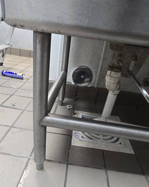 Plumbing connections under a stainless steel sink